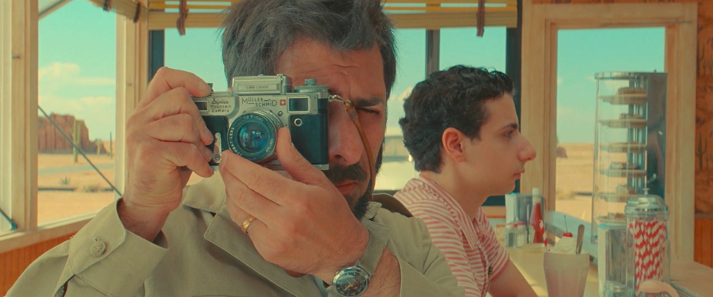 Man holding rangefinder camera in a Wes Anderson movie
