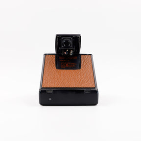 Polaroid SX-70 Alpha instant camera in black with restored caramel leather, converted to accept 600 film